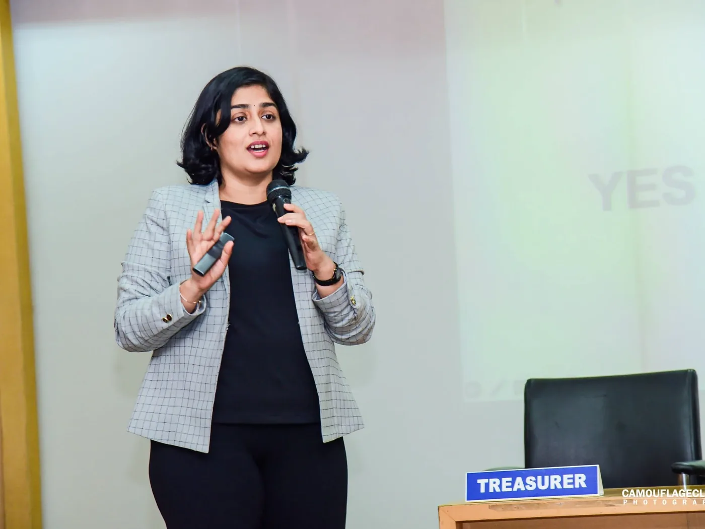Sangeetha S Abishek speaking with a microphone in front of a projected slide during a training session.