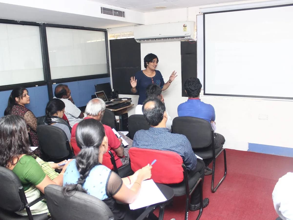 Sangeetha S Abishek teaching a seated room of participants taking notes.