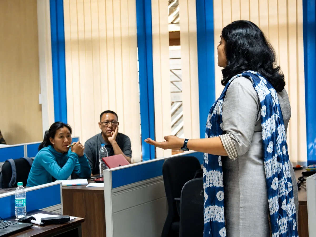 Sangeetha S Abishek teaching in a computer lab, mid-explanation to seated participants at their workstations.