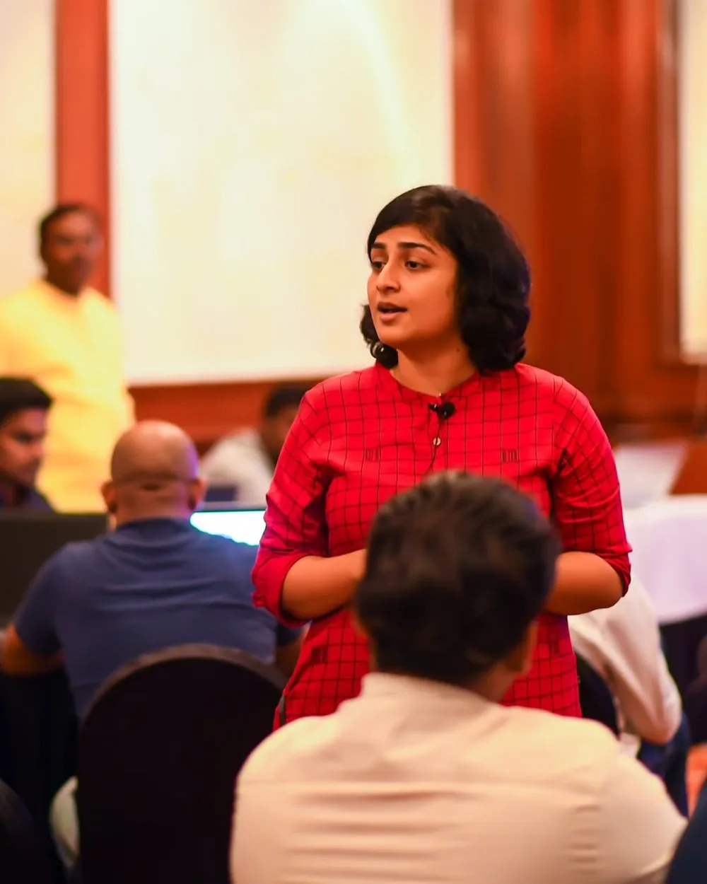 Sangeetha S Abishek teaching a full room, mid-sentence, participants at laptops around her.